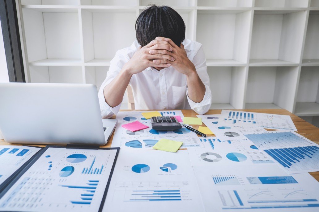 falência empresarial - homem com as mãos na cabeça e vários papéis na sua frente